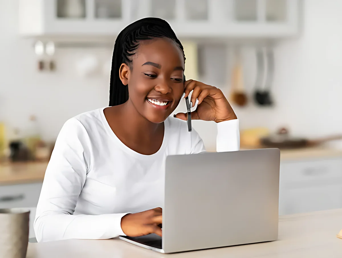 Cliente souriante au téléphone devant son ordinateur