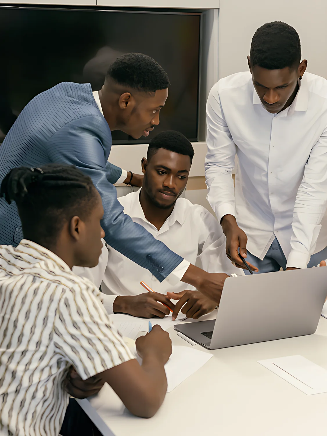 Formateur qui accompagne trois participants devant un ordinateur portable